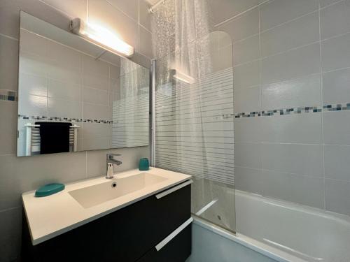 une salle de bain avec un lavabo, un miroir et une baignoire dans l'établissement T2 en front de mer - Clim - Linge inclus, à Lacanau-Océan