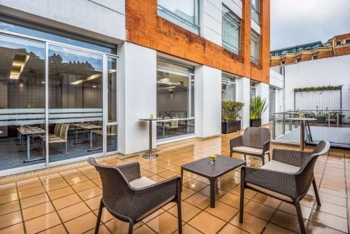 a patio with chairs and tables and windows at NH Bogota Urban 93 Royal in Bogotá