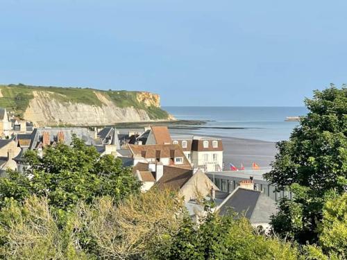un groupe de bâtiments sur une plage au bord de l'océan dans l'établissement Bellavista #3 by Melrose, à Arromanches-les-Bains