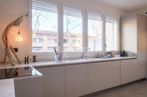 a kitchen with white cabinets and a large window at Malvasiasuites in Bologna