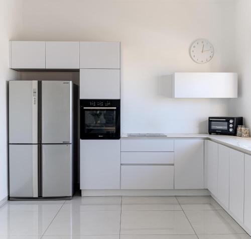 a white kitchen with a refrigerator and a clock at פנטהאוז העצמאות in Qiryat Ata