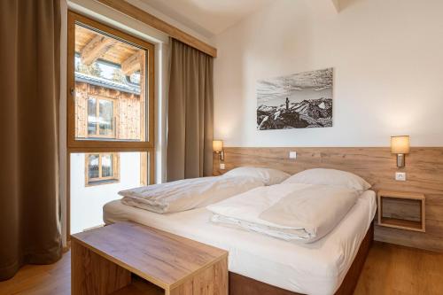 a bedroom with a bed and a table and a window at Bergresort Tauernblick by ALPS RESORTS in Mittersill