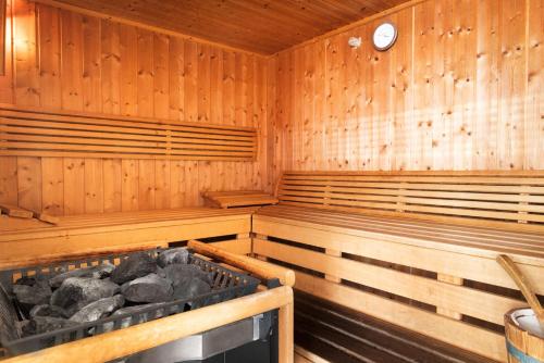 a wooden sauna with wooden benches and a clock at NH Geneva Airport Hotel in Geneva