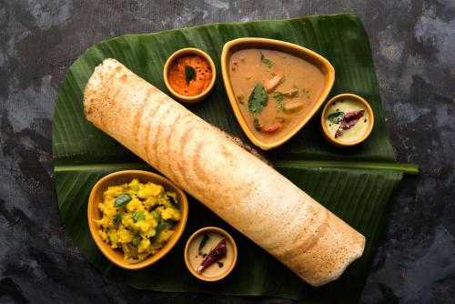 a plate of food with a burrito and soup on a banana leaf at Radisson Jaipur City Center in Jaipur