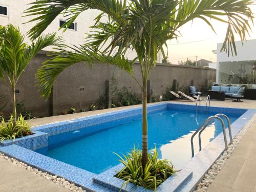 - une piscine avec un palmier à côté d'un bâtiment dans l'établissement Belrose Place, à Accra