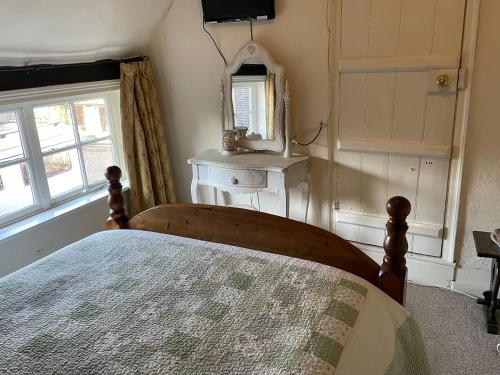 a bedroom with a bed and a mirror and a window at The Bridge Street Historic Guest House in Sudbury
