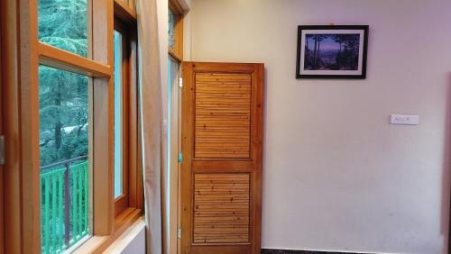 a room with a wooden door next to a window at Lill Sparrow by Verdant escapes hospitality in Dharamshala