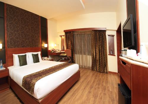 a hotel room with a large bed and a television at The Luxant Hotel in Bengaluru