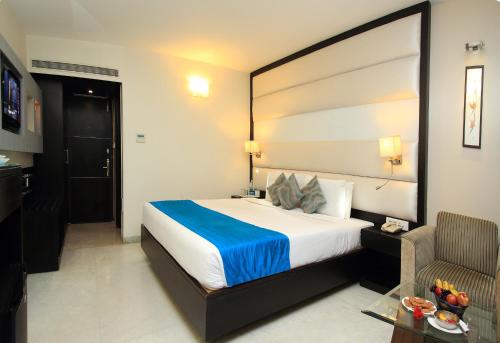 a hotel room with a large bed and a chair at The Luxant Hotel in Bengaluru