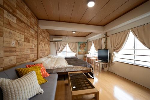 鹿児島市にあるKaibundo Apartment Hotelのベッド、ソファ、テレビのある寝室