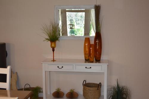 a white table with a window and vases on it at Ferienwohnung am Maienbach in Bad Bramstedt