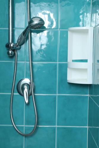 a shower head in a blue tiled bathroom at Rocca dei tramonti in Punta Braccetto