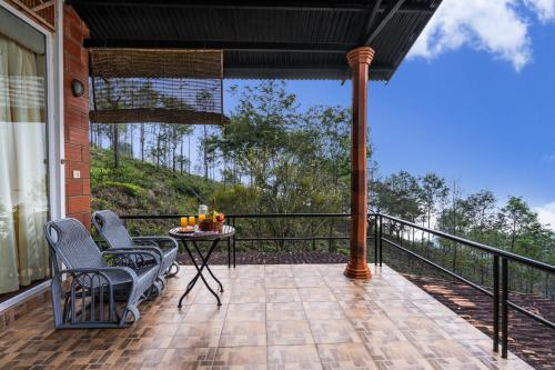 a patio with chairs and a table on a balcony at Lazy Hills by Xplore Indo in Kotagiri