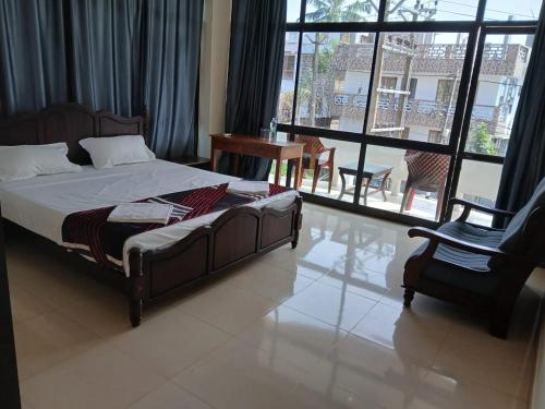 a bedroom with a bed and a chair and a window at The Travancore Palace Beach Resort in Kovalam