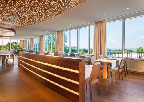 a restaurant with tables and chairs and large windows at Oberwaid - Das Hotel. in St. Gallen