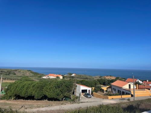 a house on a hill with the ocean in the background at Moinho da Boavista in Serra do Bouro