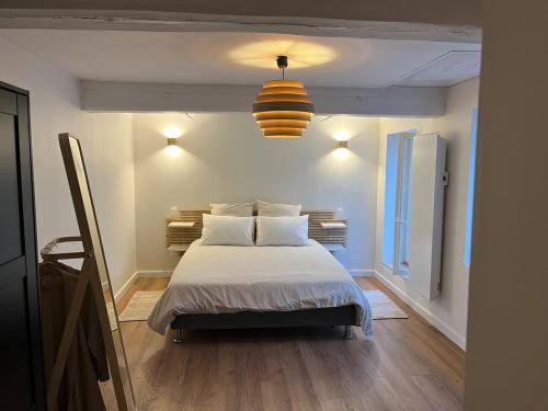 a bedroom with a bed with white sheets and a light at Le Bonhomique in Seclin