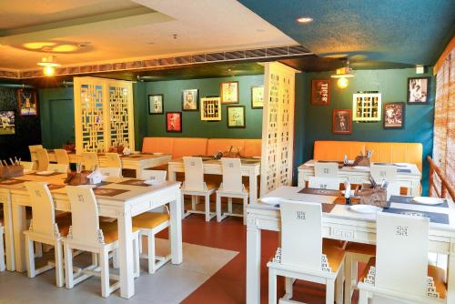 a dining room with white tables and white chairs at KGA Elite Continental Hotel in Thiruvalla