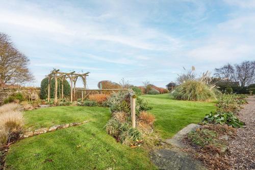 einen Garten mit einer Laube und grünem Gras in der Unterkunft Host & Stay - Newton Cottage in Alnwick