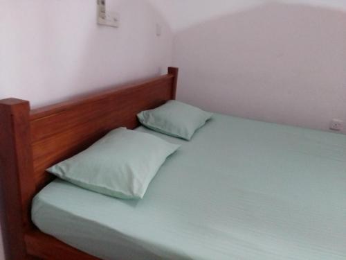 a bed with two pillows on it in a room at Pravindi Guest Home in Mirissa
