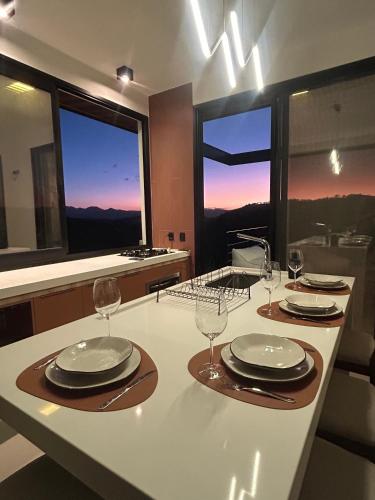 a kitchen with a table with plates and wine glasses at Solarium Mantiqueira 2 - Cinema e vistas incríveis in Itanhandu