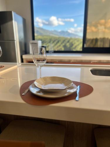 a table with a plate and a wine glass on it at Solarium Mantiqueira 2 - Cinema e vistas incríveis in Itanhandu
