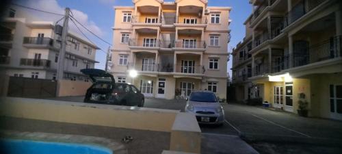 two cars parked in a parking lot in front of buildings at LKH Appt Adam Garden Villa in Grand Baie