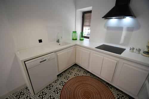 a white kitchen with a sink and a dishwasher at La Esquina del Castillo - A 15 min de Puy Du Fou in Orgaz