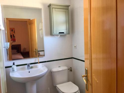 ein Badezimmer mit Toilette, Waschbecken und Spiegel in der Unterkunft Amplio adosado a 5 mits del metro y centro comercial in Mairena del Aljarafe