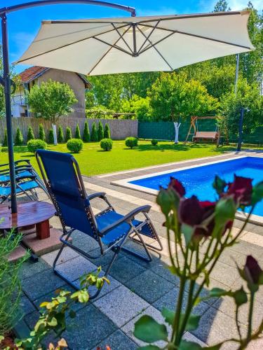 an umbrella and chairs next to a swimming pool at Vikendica Drinski LAD in Loznica