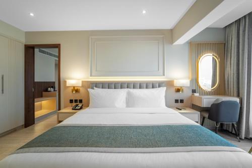 a hotel room with a bed and a desk at Grand Ambassador Hotel in Dubai