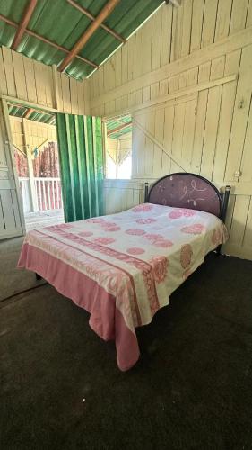 a bedroom with a bed with a pink blanket at HOSTEL MAIANDEUA in Algodoal