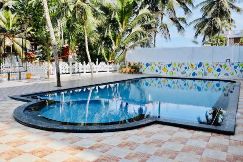 a swimming pool in the middle of a courtyard with palm trees at The Travancore Palace Beach Resort in Kovalam