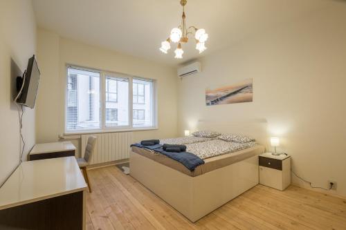 a bedroom with a bed and a desk and windows at Stylish TOP center Flat 100m to Vitosha blvd in Sofia