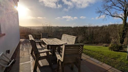a wooden table and chairs on a deck with a view at Farthings Hook Mill Holiday Cottage in Henrys Moat