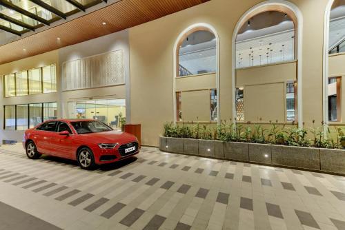 a red car parked in front of a building at The Luxant Hotel in Bengaluru