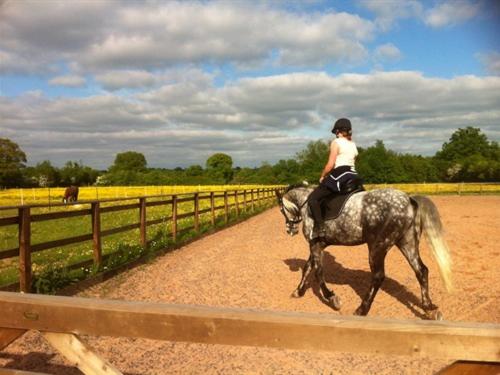 a woman riding a horse down a dirt road at The Stables - Deer Park Farm in Solihull