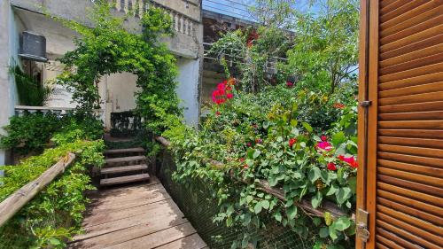 a garden with flowers and a wooden walkway at Casa Encanto do Alto Espaçosa Completa com Suíte Hidromassagem Quarto e Banheiro Extra in Mairiporã