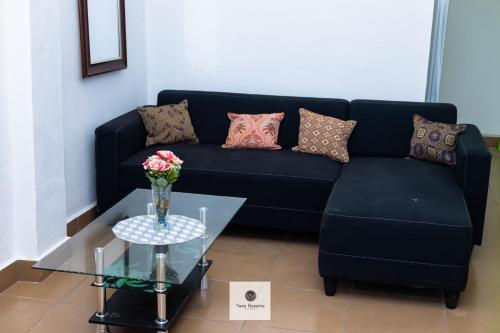 a living room with a black couch and a glass table at Nem Resorts La Résidence in Bayangam