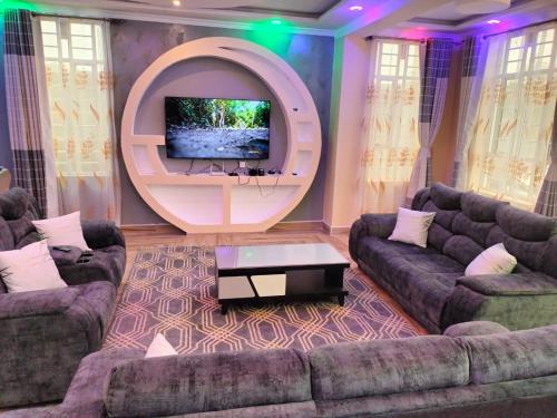 a living room with two couches and a flat screen tv at Exquisite 6 bedroom Villa in Nakuru in Nakuru