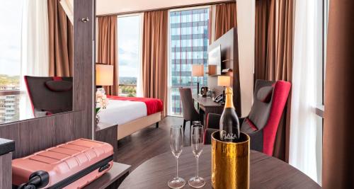 a hotel room with a bed and a table with wine glasses at PLAZA Premium Almere in Almere