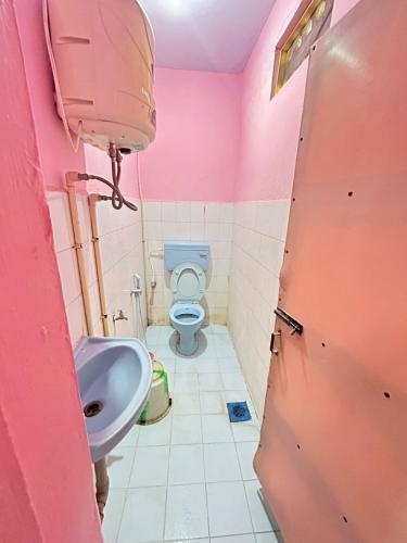 a pink bathroom with a toilet and a sink at Meera Lodge in Chidambaram