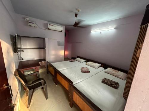 a room with two beds and a chair in it at Meera Lodge in Chidambaram