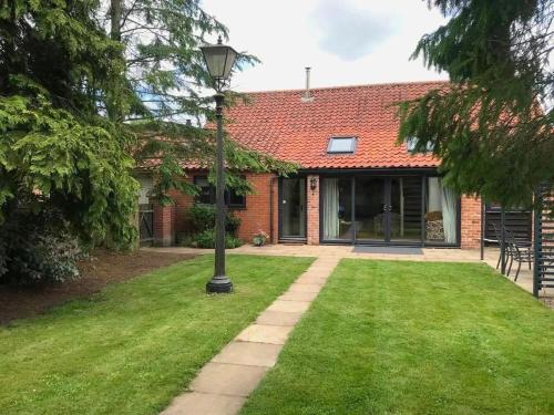 a brick house with a light pole in the yard at Barn with countryside views in private garden in Norwich