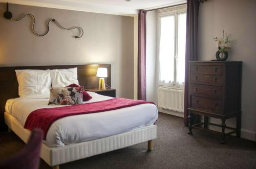 a bedroom with a bed and a dresser and a window at Le Franklin in Paris