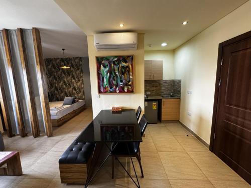 a living room with a couch and a table and a kitchen at Roots Hotel Apartment in Accra