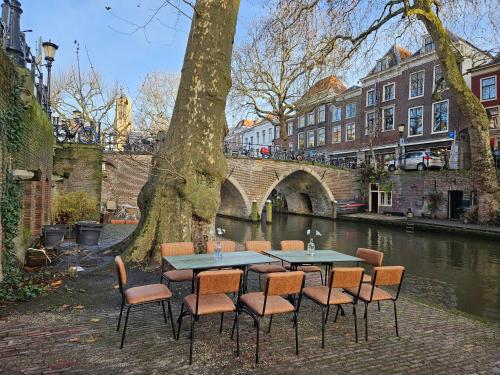 a table and chairs next to a river with a bridge at Overnachten aan de Werf in Utrecht