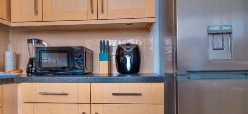a kitchen with a stainless steel refrigerator and a microwave at Cosy Home-Sleeps 5- Private Garden- Free Parking in Corby