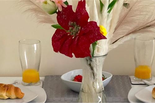 eine Vase mit einer roten Blume auf einem Tisch in der Unterkunft Cosy Home-Sleeps 5- Private Garden- Free Parking in Corby