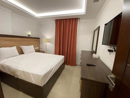 a hotel room with a bed and a flat screen tv at Grand Plaza Sheikh Zayed in Kafr Abū ʼumaydah
